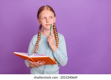 Photo of thoughtful creative pupil girl hold notebook look empty space wear blue shirt isolated violet color background
