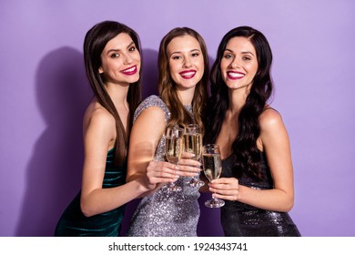 Photo of three adorable sisters hold glasses cheering make toast wear glossy dresses isolated purple color background