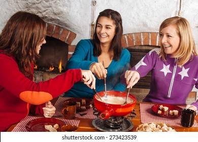 Foto von drei schönen Weibchen, die Brot in den geschmolzenen Käse in einem Fondue Topf.