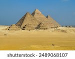 A photo of the three famous pyramids at Giza Necropolis, Egypt. The Great Pyramid of Giza, the largest pyramid in the Giza Plateau, is in the center.