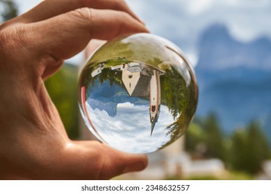 Photo through a glass ball. Church of San Giacomo. Ortisei, Gardena Valley, South Tyrol, Dolomites, Italy, Europe.