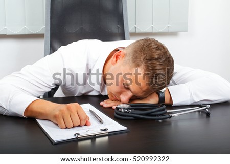  Photo of a tired young male doctor in his medical office