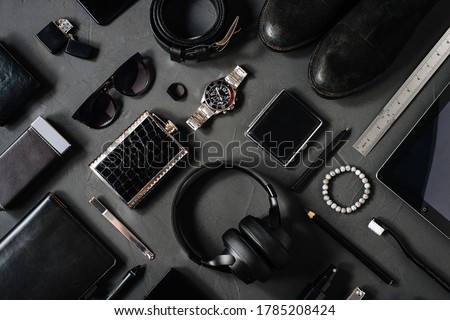 Photo topview flat lay modern style of men every day carry stuff accessories headphones camera facial mask bracelet lighter purse sunglasses tablet camera phone boots leather belt on dark background