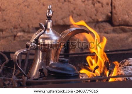 Photo of traditional arabic tea pot in the fire for warming it. Bedouin tea, traditional tea