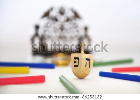 Photo of a traditional wooden dreidel (spinning top), a bronze menorah, and colorful candles isolated on white background.  Group of objects symbolizing Hanukkah Jewish Holiday. No people. Copy space.