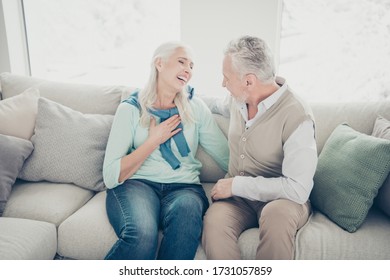 Photo of two aged people pair spending free time together listen humorous stories sitting cozy sofa indoors
