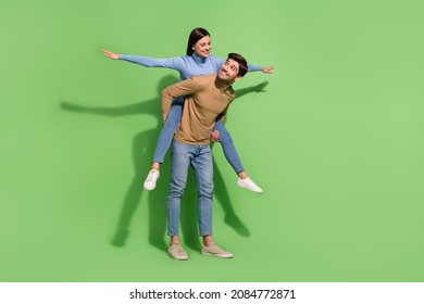 Photo Of Two Carefree People Guy Carry Piggyback Lady Show Plane Pose Wear Casual Outfit Isolated Green Color Background