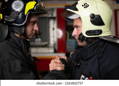 Photo of two firemen wearing helmets waving their handshake