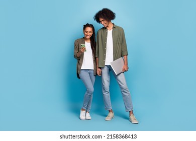 Photo of two friends partners hold netbook use smart device search network news wear jeans isolated blue color background