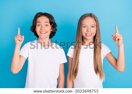 Photo of two genius kids have idea raise fingers show empty space wear white t-shirt isolated blue color background