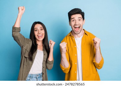 Photo of two nice young partners raise fists shout yes wear shirt isolated on blue color background - Powered by Shutterstock