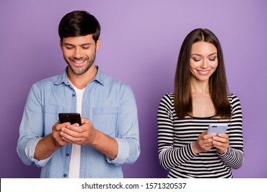 Photo of two people couple guy lady holding telephones counting likes followers reposts shares addicted social network users wear casual outfit isolated purple color background