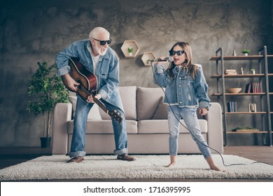 Photo Of Two People Excited Grandpa Play Guitar Small Granddaughter Mic Singing Cool Style Trendy Sun Specs Denim Clothes Repetition School Concert Stay Home Quarantine Living Room Indoors