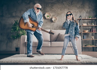 Photo Of Two People Grandpa Play Guitar Small Granddaughter Mic Singing Rejoicing Cool Style Trendy Sun Specs Denim Clothes Repetition School Concert Stay Home Quarantine Living Room Indoors