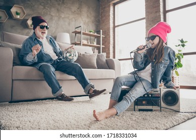 Photo Of Two People Grandparent Little Granddaughter Cool Vintage Style Specs Denim Outfit Hat House Party Sit On Tape Player Recorder Sing Mic Old Fashion Song Stay Home Quarantine Indoors