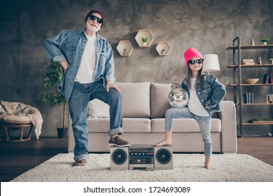 Photo Of Two People Grandparent Little Granddaughter Cool Vintage Style Sun Specs Denim Outfit Hat House Party Listen Tape Player Leg On Recorder Stay Home Quarantine Living Room Indoors