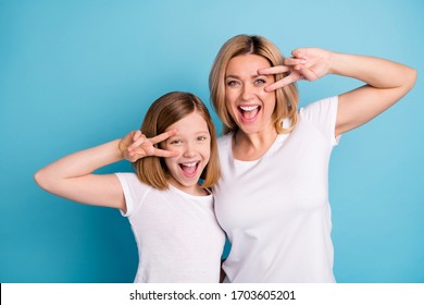 Photo Of Two People Young Beautiful Mom Lady Small Daughter Good Mood Showing V-sing Symbols Near Eyes Saying Hi Friends Wear Casual White S-shirts Isolated Blue Color Background