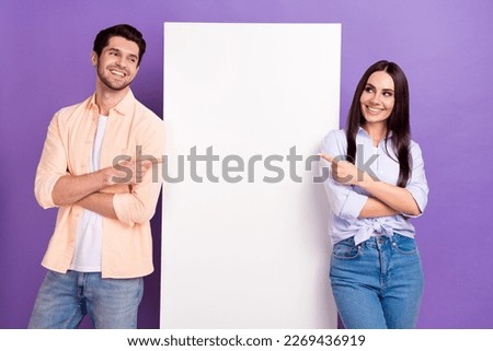 Photo of two positive attractive people look indicate fingers empty space placard isolated on violet color background