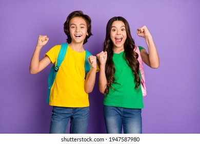Photo Of Two School Kids Happy Positive Smile Celebrate Win Victory Fists Hands Hold Rucksack Isolated Over Violet Color Background