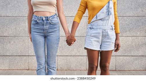 Photo of two unrecognizable multi-ethnic girlfriends holding hands. Multicultural young homosexual women couple together outdoors. Lesbian relations female gen z people. Copy space and background. - Powered by Shutterstock