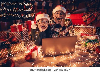 Photo of two young astonished funny partners use laptop festive christmas illumination apartment indoors - Powered by Shutterstock