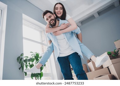 Photo of two young partners smile piggyback relocating moving box package new modern flat indoors - Powered by Shutterstock