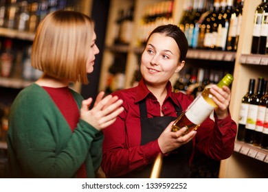 Photo of two young women with bottle in hands at liquor store