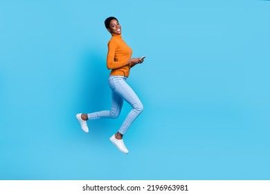 Photo Of Unisex Person Hold Telephone Jump Have Fun Wear Yellow Shirt Isolated Blue Color Background