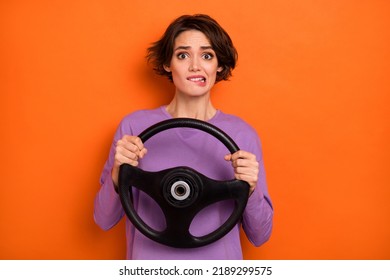 Photo Of Unsatisfied Worried Person Biting Lip Hands Hold Wheel Isolated On Orange Color Background