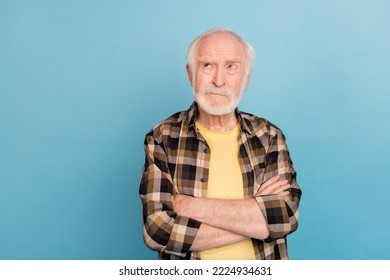 Photo of unsure funny retired man wear plaid shirt arms folded looking empty space isolated blue color background