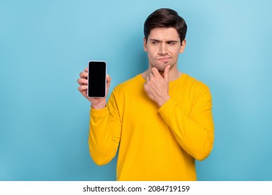 Photo Of Unsure Guy Dont Know Buy New Smart Phone Device With Many Apps Touch Hand Chin Isolated Over Blue Color Background