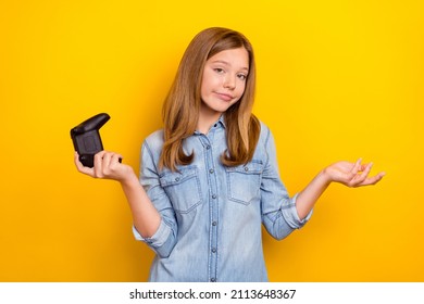 Photo Of Unsure Teen Brown Hairdo Girl Hold Playstation Wear Denim Shirt Isolated On Bright Yellow Color Background