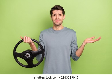 Photo Of Unsure Young Brunet Guy Drive Car Shrug Shoulders Wear Grey Pullover Isolated On Green Color Background