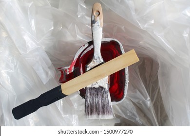 Photo Of A Used Paint Brush, Wooden Stirrer And Plastic Pail, On A Tarp. Shows Home Improvement Concept.