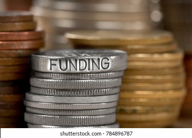 Photo of various stacks and rows of coins with FUNDING concept word imprinted on metal surface