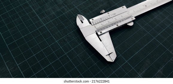 Photo of a vernier caliper with centimeters and millimeters. 
				on a green background cutting mat