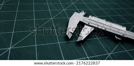 Photo of a vernier caliper with centimeters and millimeters. 
on a green background cutting mat