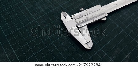 Photo of a vernier caliper with centimeters and millimeters. 
on a green background cutting mat