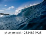 In the photo, vibrant turquoise waves crash against the sun-kissed shores of Telo Island, Indonesia. A lone surfer, silhouetted against the setting sun, rides a majestic wave with effortless grace.