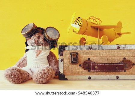 Photo of vintage toy plane and cute teddy bear on wooden table