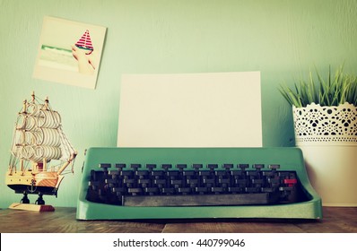 Photo Of Vintage Typewriter With Blank Page On Wooden Table. Retro Filtered And Toned Image