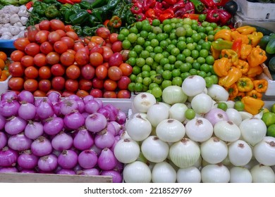 Photo Of White And Purple Onions, Limes, And Tomatoes Stacked Up On Display In A Market.