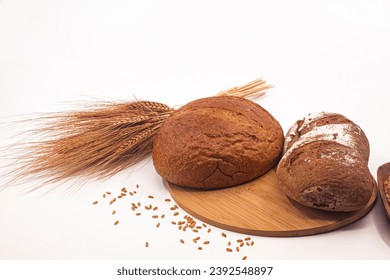 Photo of whole wheat breads, wheat ears and wheat grains on white background.