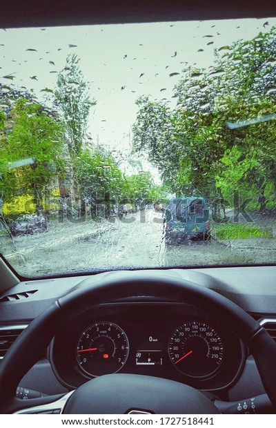 Photo of the windshield, steering\
wheel and driver\'s seat. Rain in autumn. Morning\
photo.