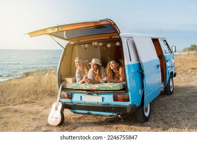 Photo wit copy space of a camper van parked on a beach with friends lying inside - Powered by Shutterstock