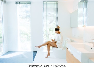 Photo Of Woman Applying Body Lotion To Her Legs After Shower In Luxury Bathroom