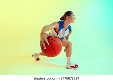 Photo of woman in blue and white basketball jersey, focused and dribbling ball in neon light against gradient studio background. Concept of sport, championship, tournament, hobby and recreation. Ad - Powered by Shutterstock