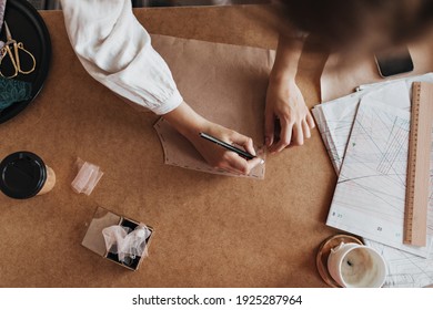 Photo of woman designing pattern. Brunette lady in white shirt creating new fashion collection in her cozy office