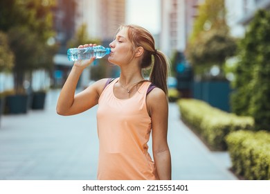 Photo of Woman drinking water from bottle. Caucasian female drinking water after exercises or sport. Beautiful fitness athlete woman wearing hat drinking water after work out exercising on sunset - Powered by Shutterstock