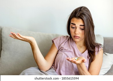 Photo of a woman holding bunch of pills in hand,looking at them,taking painkiller to relieve painful feelings migraine headache,antidepressant or antibiotic medication.Medicine and healthcare concept. - Shutterstock ID 1855615594